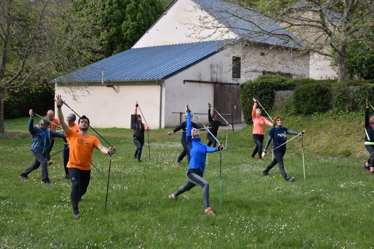 Atelier en plein air : exercices avec bâtons dans une prairie devant une grange