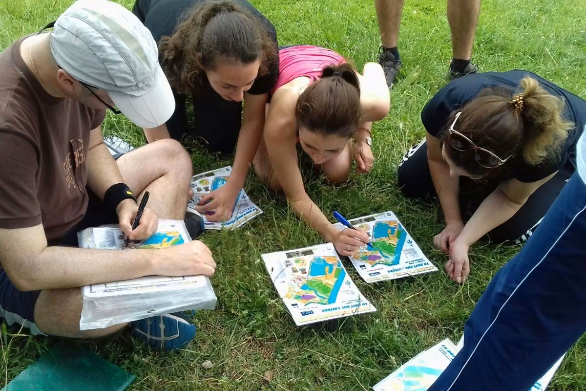Atelier orientation : participants penchés sur des cartes dans l’herbe