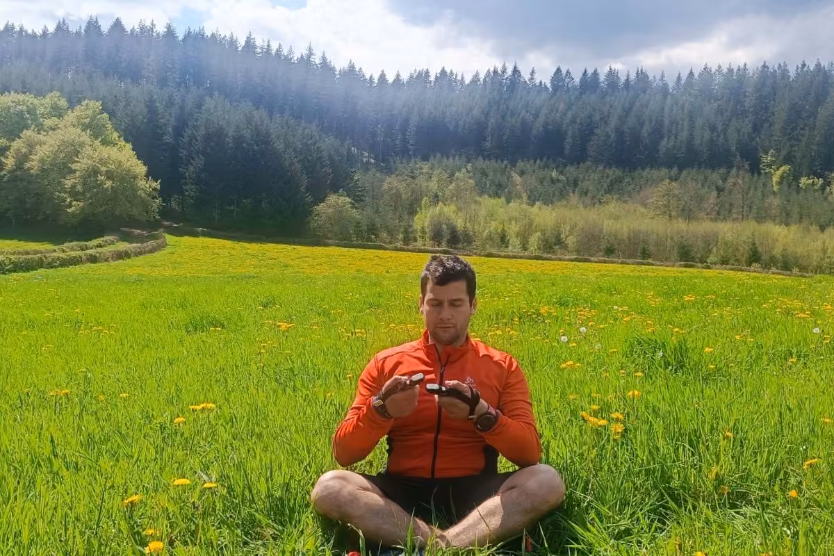 Atelier respiration : Kévin assis en tailleur, mains jointes, dans une prairie