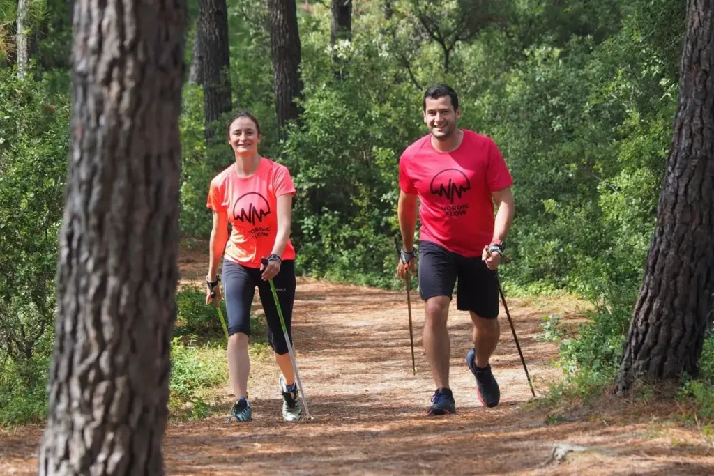 Deux marcheurs côte à côte en forêt, en gardant la gestuelle de la marche nordique