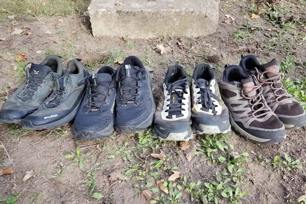 Quatre paires de chaussures de marche nordique alignées sur l’herbe : Salewa, Asics Gore-Tex, trail Kiprun et randonnée basse Columbia