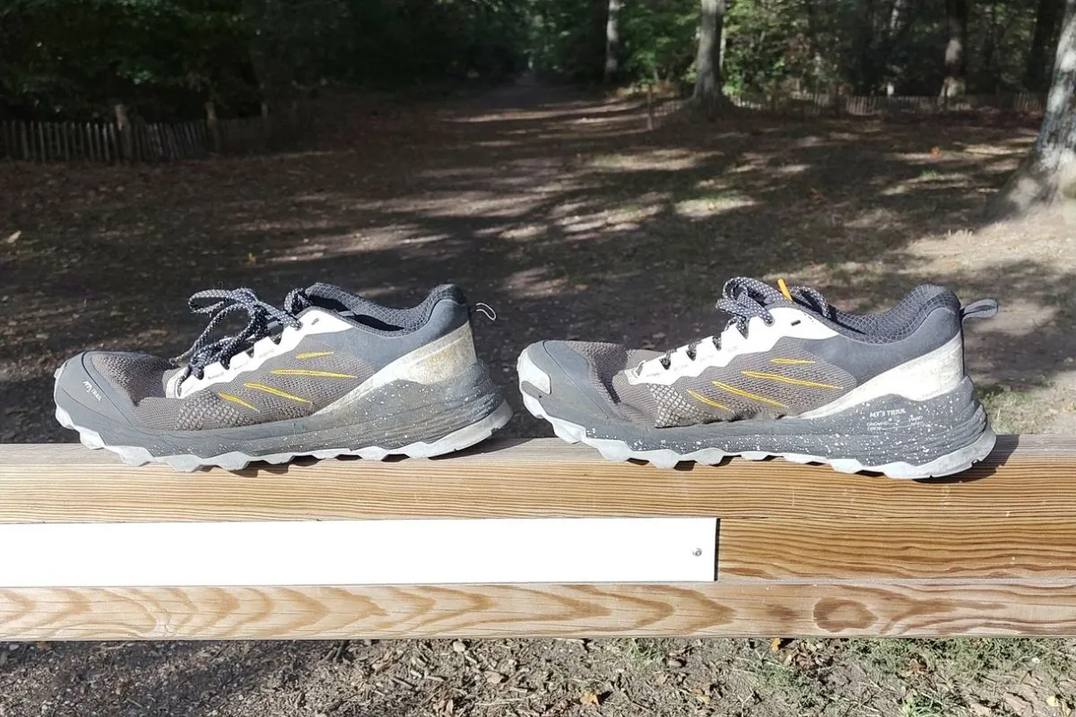 Paire de chaussures de trail usées, semelle blanchie, posée sur une barrière en forêt de Sénart