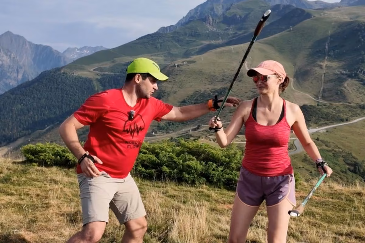 Le coach tend un bâton à une participante pour ajuster le geste