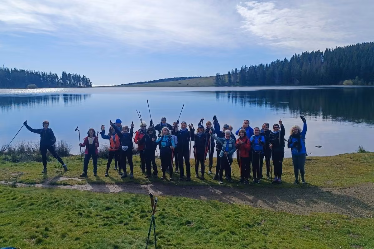 Groupe bras levés au bord du lac de la Servière, ciel clair
