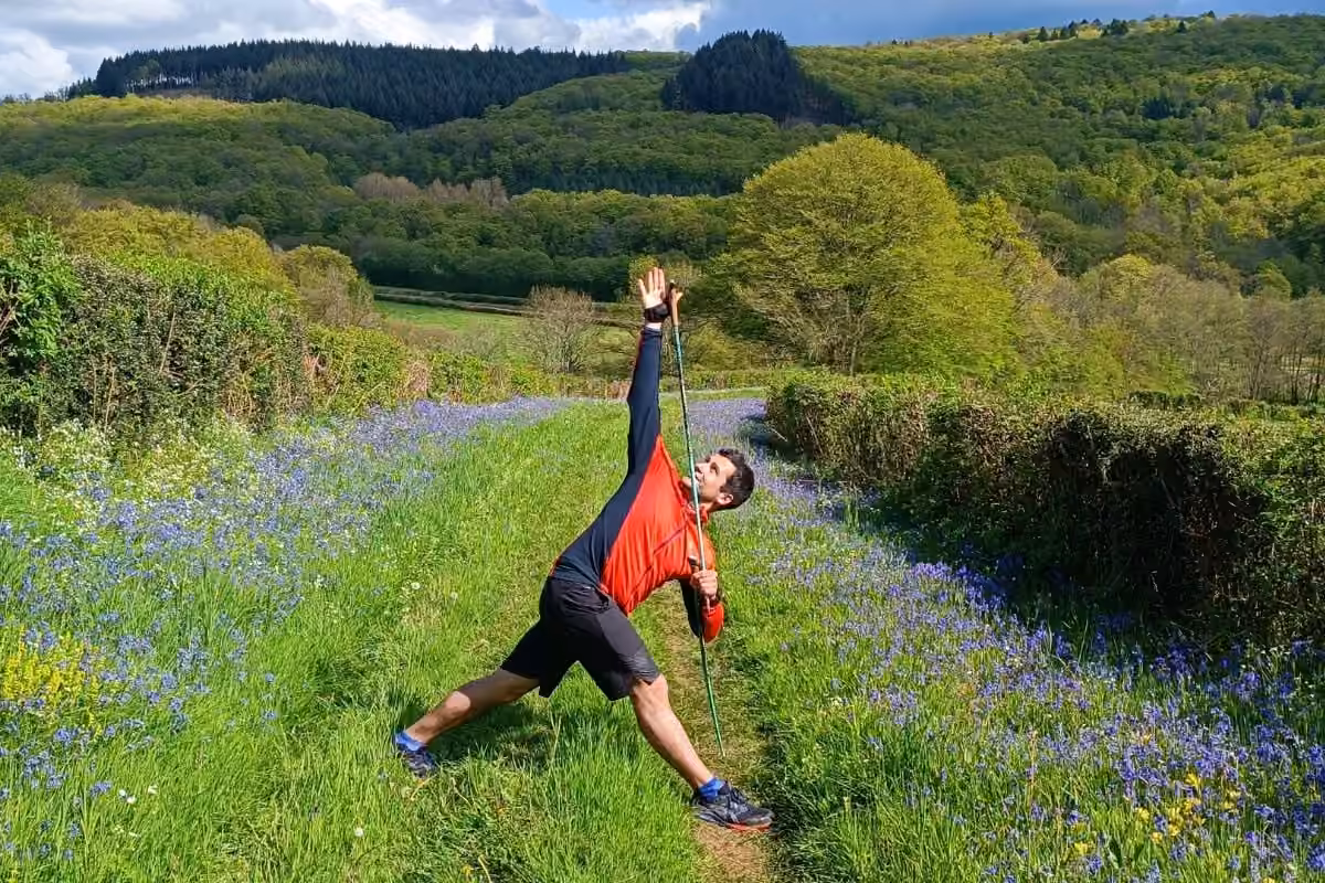 Posture du triangle avec bâton sur un chemin de jacinthes sauvages