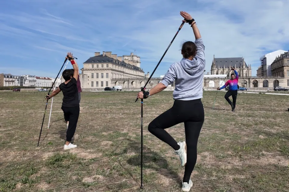 Posture d’équilibre en Nordic Yoga® avec bâtons devant le château de Vincennes