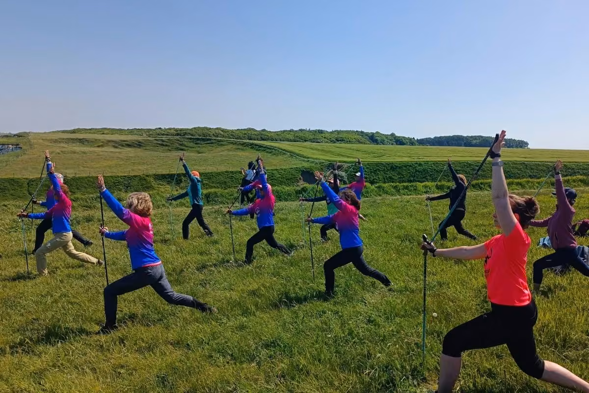 Groupe en fente avant avec bâtons dans une prairie, ciel dégagé