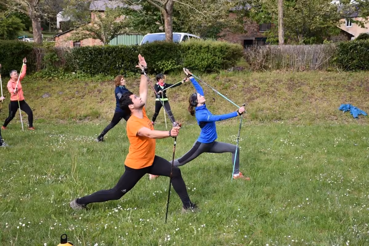 Atelier Nordic Yoga : groupe en fentes avec bâtons dans une prairie