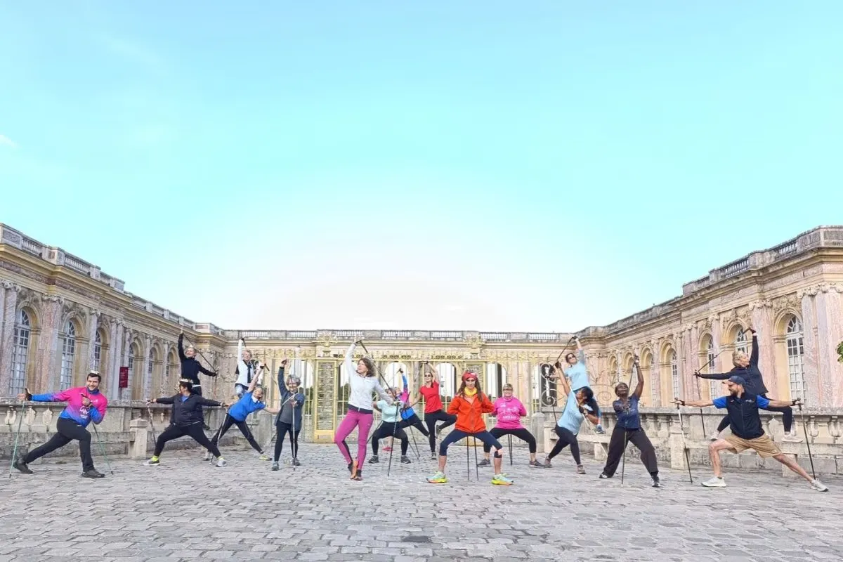 Groupe Nordic Flow en posture du guerrier avec bâtons dans la cour du Grand Trianon à Versailles